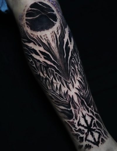 Tatuaje blackwork en Barcelona con diseño de criatura demoníaca de dientes afilados y detalles oscuros en el antebrazo. Realizado en Black Haru Tattoo Studio.