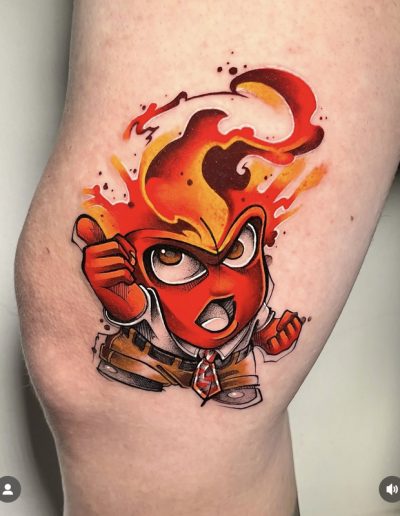 Tatuaje en estilo acuarela de un personaje con rostro rojo y llamas emergiendo de su cabeza, transmitiendo una expresión de ira y determinación. El diseño incluye detalles en tonos cálidos como rojo, naranja y amarillo, con un efecto de salpicaduras y difuminados que realzan la intensidad del fuego. El personaje viste camisa blanca, pantalones marrones y una corbata roja, aportando contraste y dinamismo al tatuaje.