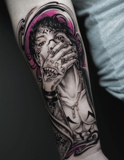 Tatuaje en estilo realista con elementos surrealistas en el antebrazo de una persona. La imagen representa a un hombre con el torso descubierto, joyería y tatuajes, cubriéndose la boca con una mano que tiene tatuada la palabra "ARMY" y una boca adicional dibujada sobre ella, generando un efecto perturbador. La composición en negro y gris se complementa con acentos en color rosa vibrante, creando un contraste llamativo.