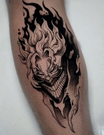 Tatuaje anime en blanco y negro en Barcelona con diseño de personaje siniestro en llamas. Líneas detalladas y sombras intensas en Black Haru Tattoo Studio.