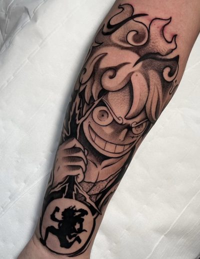 Tatuaje anime en blanco y negro en Barcelona con diseño de personaje icónico en el antebrazo. Líneas audaces y sombreado dinámico en Black Haru Tattoo Studio.