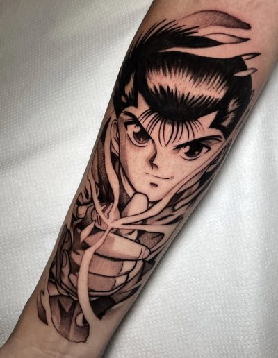 Tatuaje anime en blanco y negro en Barcelona con diseño detallado de personaje icónico en el antebrazo. Sombras profundas y líneas precisas en Black Haru Tattoo Studio.