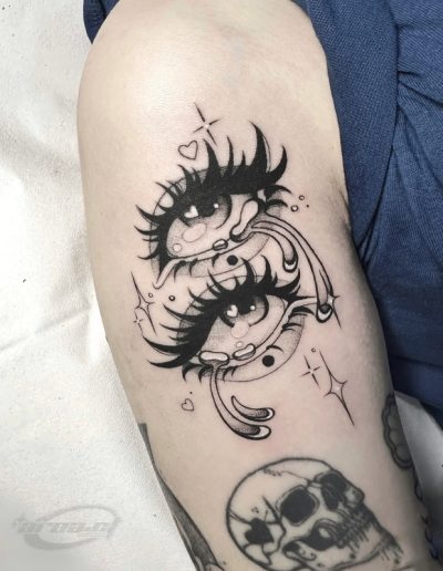 Tatuaje blackwork en Barcelona con diseño de ojos llorosos y detalles brillantes en el brazo. Líneas audaces y sombreado intenso en Black Haru Tattoo Studio.