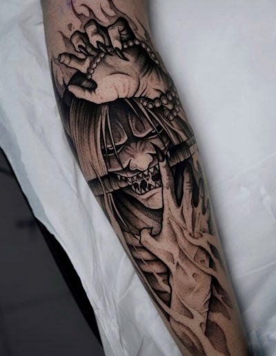 Tatuaje blackwork en Barcelona con diseño de demonio japonés y manos en sombras. Detalles intensos y líneas profundas en Black Haru Tattoo Studio.