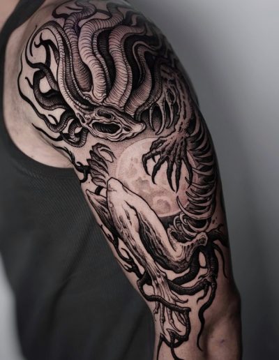 Tatuaje blackwork en Barcelona con diseño de criatura oscura y elementos terroríficos en el brazo. Detalles intensos y sombras profundas en Black Haru Tattoo Studio.
