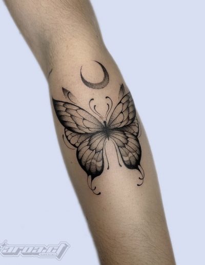 Tatuaje fineline en Barcelona con diseño de mariposa sombreada y luna en el antebrazo. Trazos delicados y estilo minimalista en Black Haru Tattoo Studio.