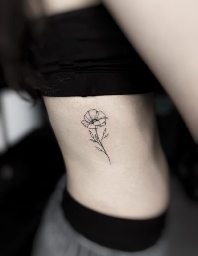 Tatuaje de estilo fineline en Barcelona con diseño minimalista de una flor en la zona de las costillas. Realizado en Black Haru Tattoo Studio.